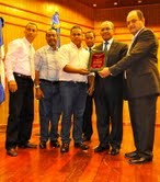 El profesor Ángel Silverio y el director del centro puerto plata, Ramón Racer Lantigua entregan la placa de reconocimiento al señor rector Mateo Aquino Febrillet en representación de los profesores del centro.