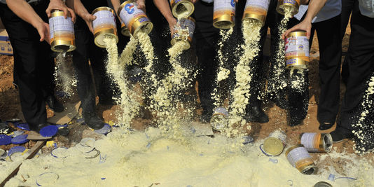 Des agents de l'inspection sanitaire vident des boîtes de lait en poudre contaminé dans une décharge de la province chinoise de Guangdong, le 19 septembre 2008. | Stringer Shanghai / Reuters