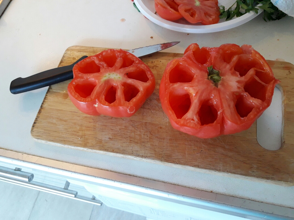 Tagliare la parte superiore dei pomodori e conservarla perché verrà utilizzata per ricoprire il ripieno. Scavare con un dito il pomodoro conservando la struttura come in foto e togliendo quanto più possibile la parte molle.