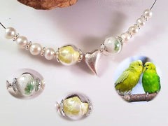 CO 4: 11 mm Glasperlen mit Federn und Süsswasserperlen zu einem Collier gefertigt. Das Herz, die Perlkappen und die Zwischenspacer sind aus 925er Silber.Aufgezogen auf nylonumantelten Edelstahldraht. Verschluss ebenfalls aus 925er Silber. Preis: 90 Euro