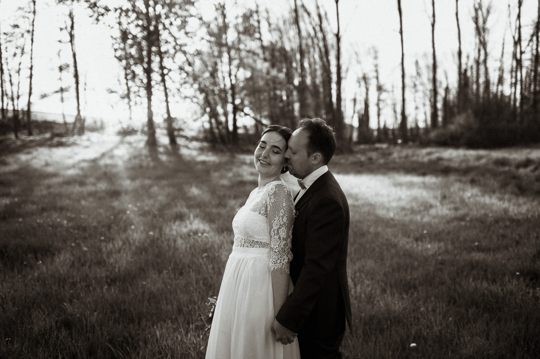 Paarfotos bei Zollling. Der Bräutigam steht hinter der lachenden Braut. Hochzeitsfotograf ist Andreas Reiter.
