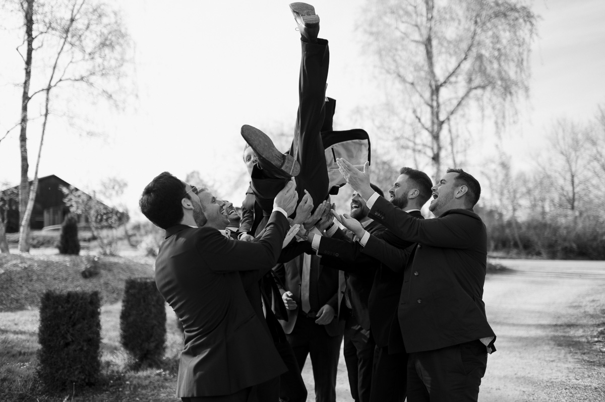 Groomsmen werfen den Bräutigam in die Luft