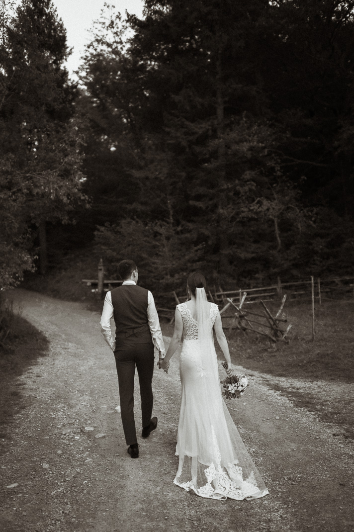 Das Brautpaar geht einen Weg entlang beim Brautpaarshooting am Schliersee.