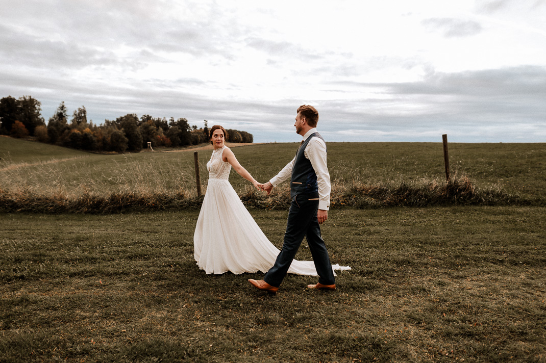 Abendliche Harmonie: Schwarzweiß-Aufnahme eines verliebten Brautpaars auf einer weiten Wiese in Gut Thurnsberg, fotografiert von Mr & Mrs Wedding