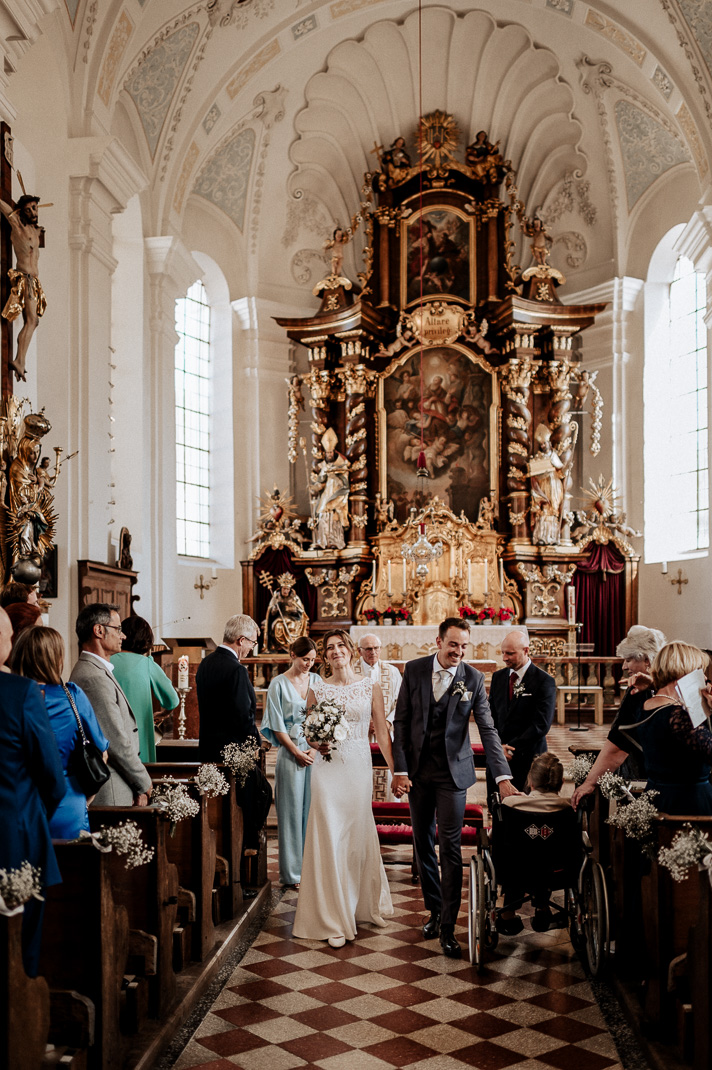 Hochzeitsfotograf in der St. Sixtus Kirche am Schliersee. Das Brautpaar zieht aus der Kirche aus. Reportagefoto von der Trauung.