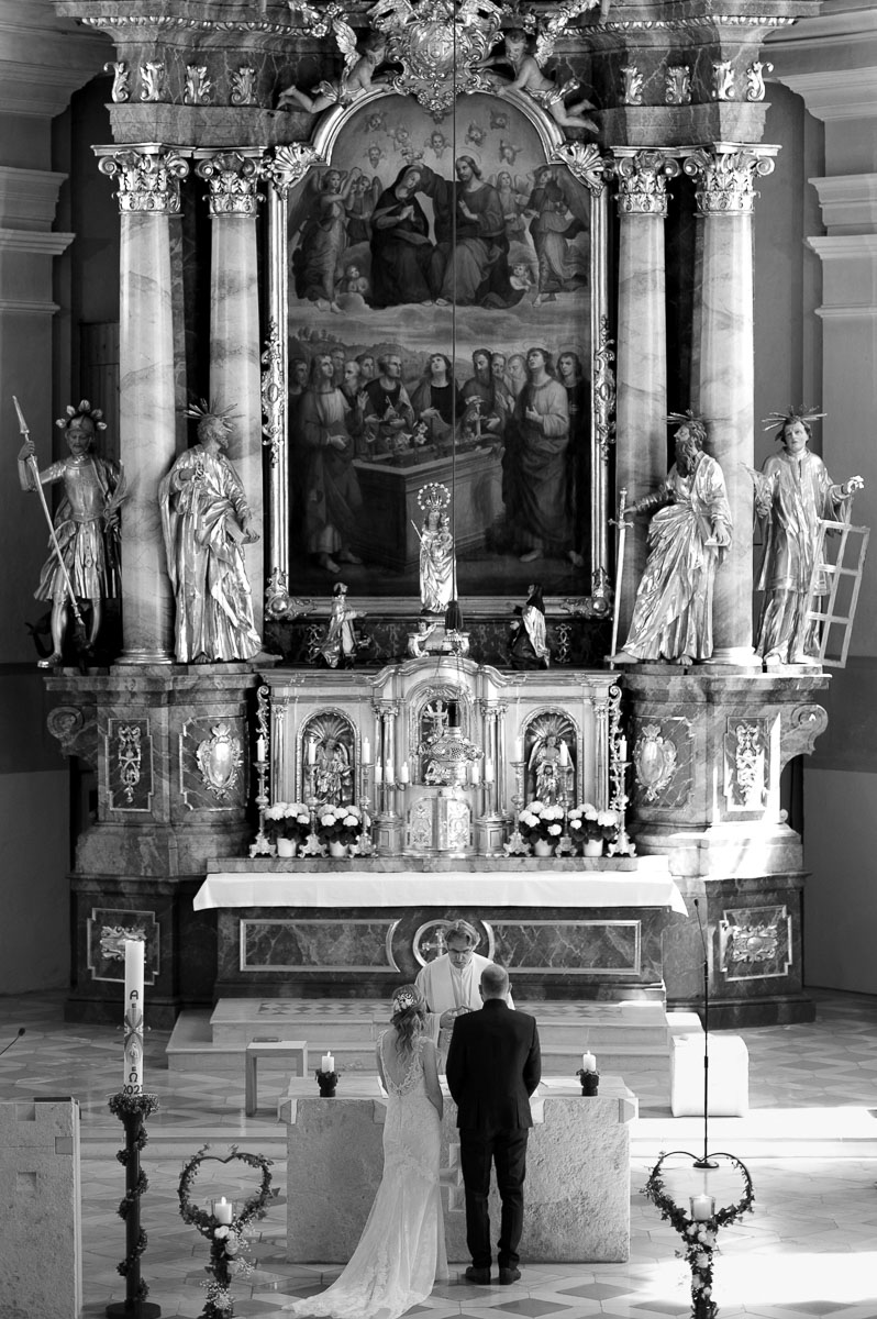 Das Brautpaar steht am Altar einer Kirche bei einer kirchlichen Hochzeit.