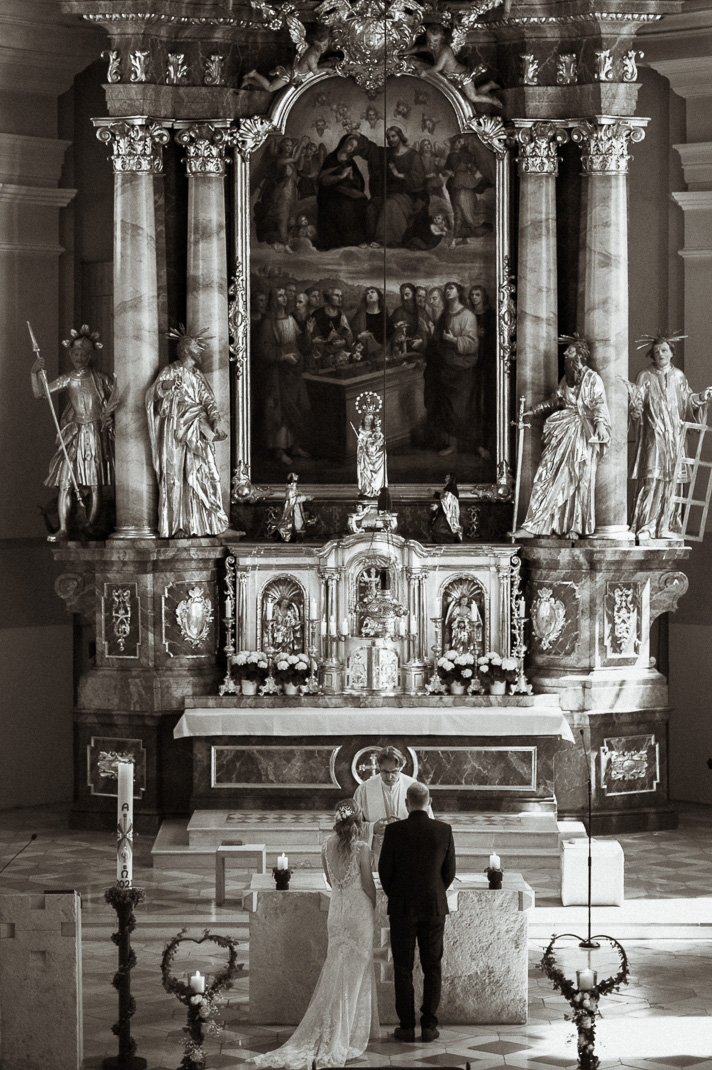 Das Brautpaar steht am Altar einer Kirche bei einer kirchlichen Hochzeit.