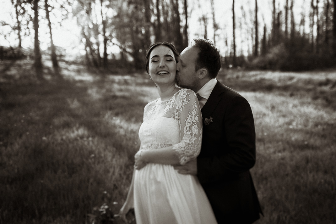 Paarfotos auf einer Wiese bei Zolling. Der Bräutigam steht hinter der Braut. Hochzeitsfotograf ist Andreas Reiter.