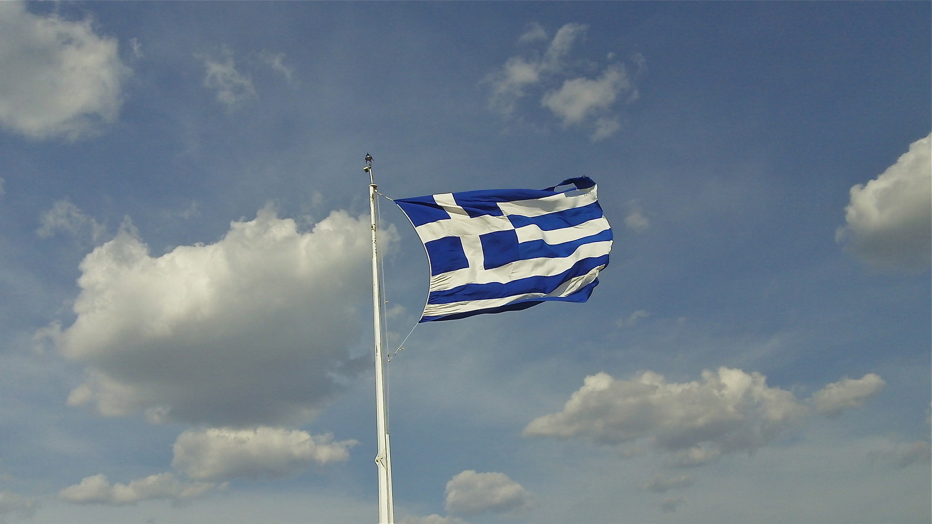 the Greek flag waves in the breeze at the Acropolis