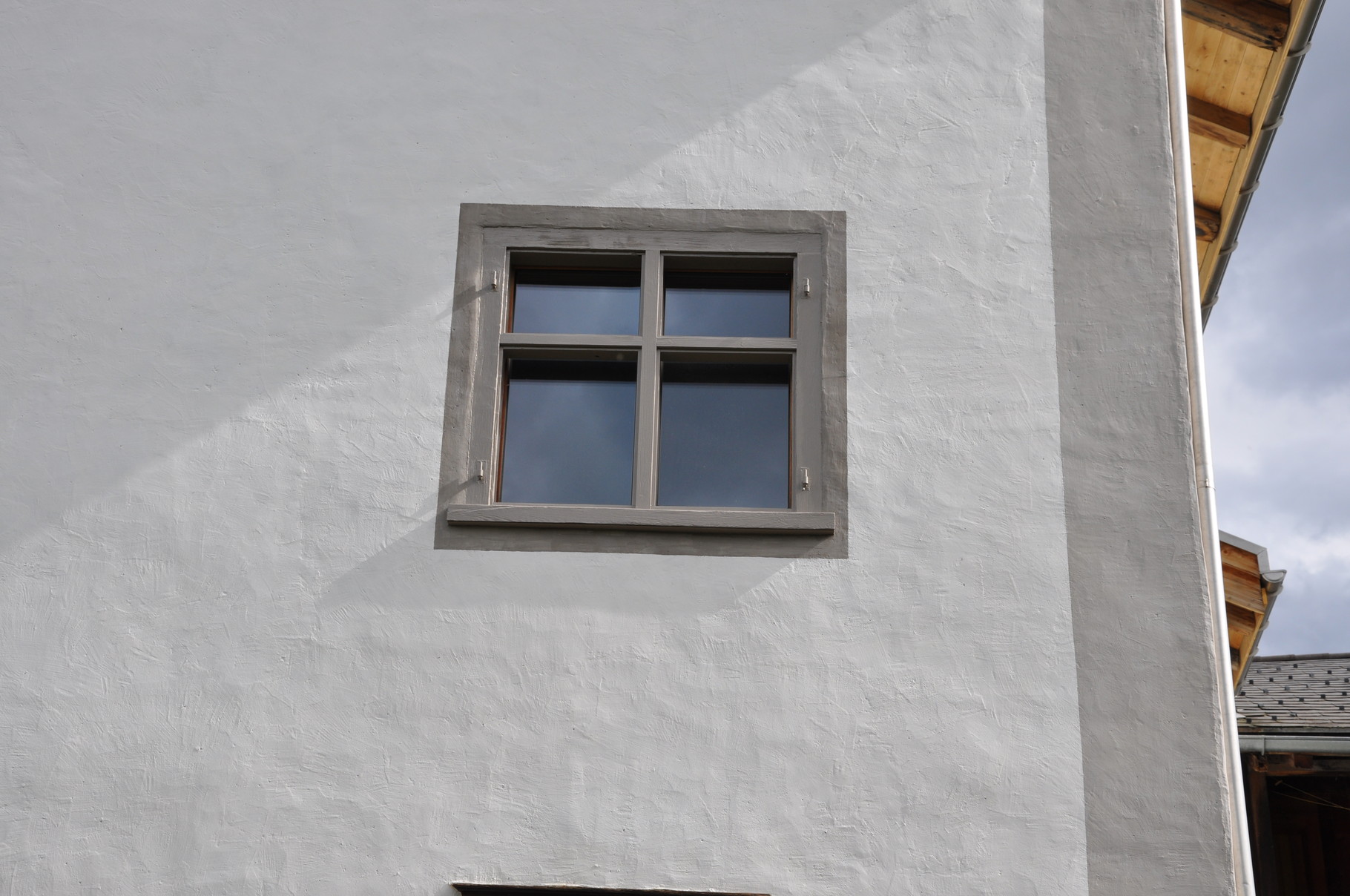 Detail Kalkputz mit aufgemalten Ecklisenen und Fenstereinrahmungen in versch. Grautönen