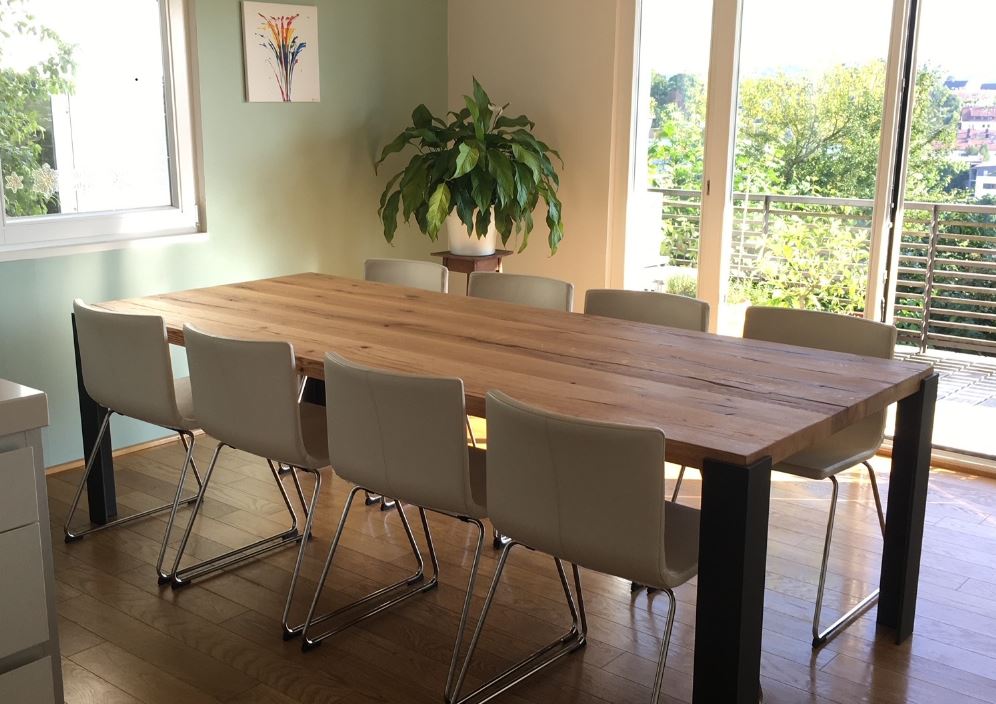 Schlichter Esstisch aus Altholz mit außenstehenden Metallbeinen für modernes Wohndesign.
