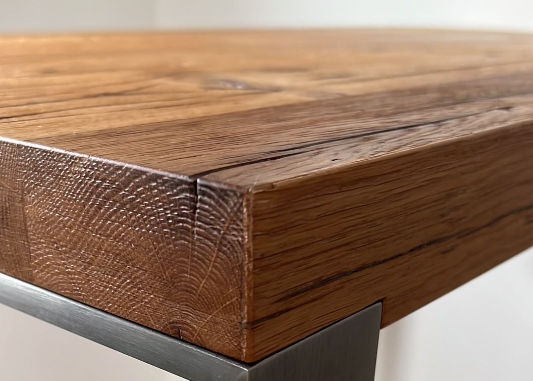 Detailaufnahme einer Tischplatte aus Altholz mit markanten Rissen, Ästen und authentischer Maserung.