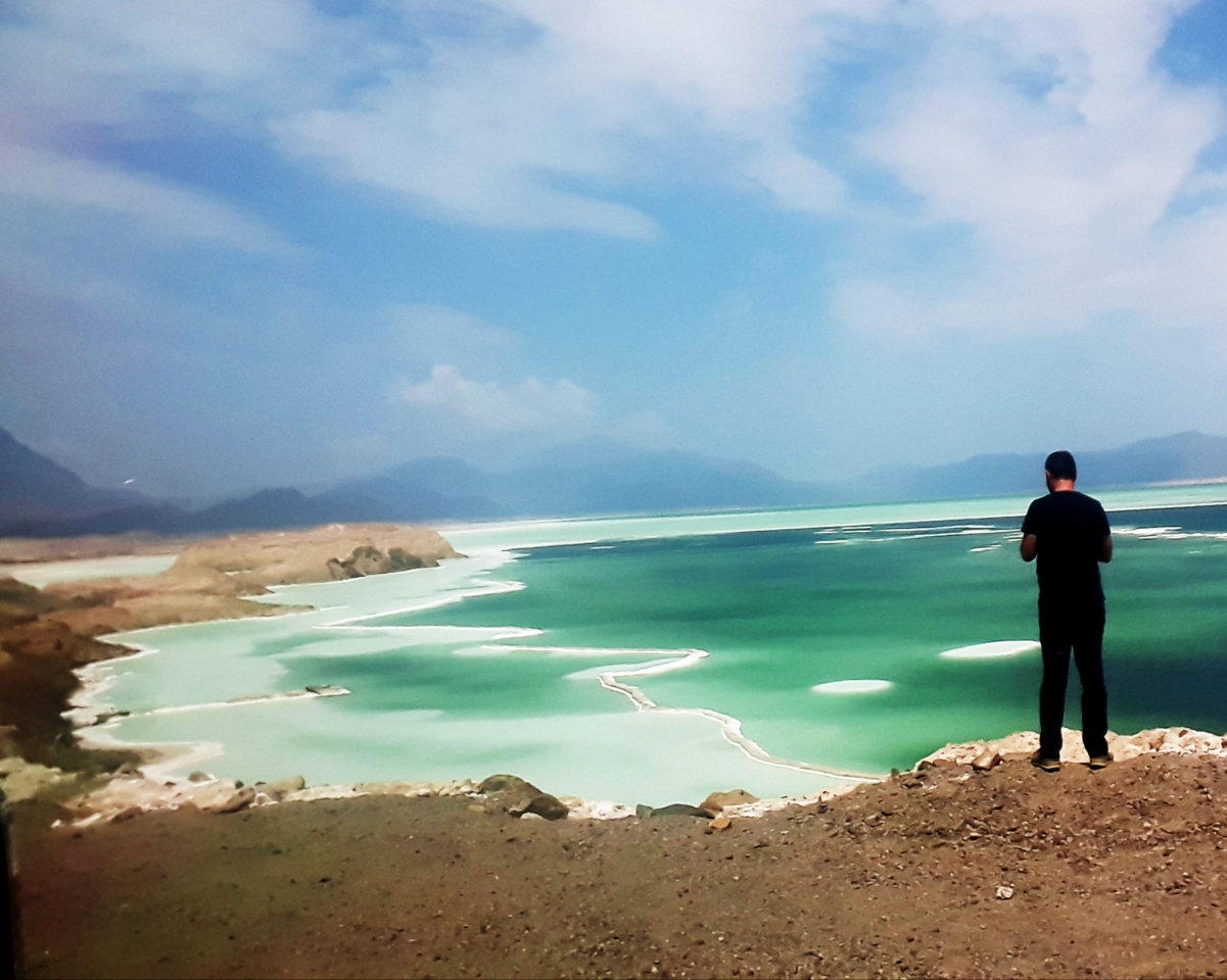 Lake Assal (Arabic, Buḥayrah ʿAsal, literally 'honey lake') is a crater lake in central-western Djibouti . It is located at the western end of Gulf of Tadjoura in the Tadjoura Region , touching Dikhil Region , at the top of the Great Rift Valley, some 120 km (75 mi) west of Djibouti city . Lake Assal is a saline lake which lies 155 m (509 ft) below sea level making it the lowest point on land in Africa and the third-lowest point on Earth after the Sea of Galilee and the Dead Sea. No outflow occurs from the lake, and due to high evaporation, the salinity level of its waters is 10 times saltier than the water of the sea, making it the second most saline body of water in the world .