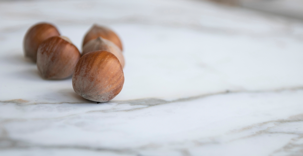 Hazelnuts on white marble worktop 