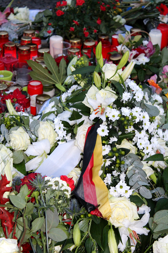 Ein Deutschland-Fähnchen inmitten von Blumen und Kerzen nach dem Terror-Anschlag in Paris. Foto: Helga Karl