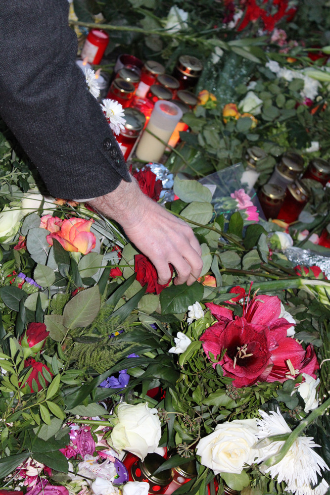 Arm eines Mannes - er legt Rote Rosen auf das Blumenmeer vor franz. Botschaft. Foto: Helga Karlot