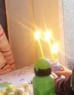 Drei Kinder im Alter von 3 bis 5 Jahren mit offenen Kerzen.