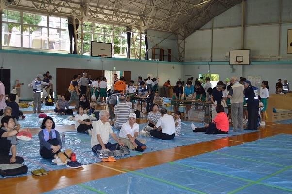 皆さん、このような形で避難します。この日は体育館はスポット冷房と大型扇風機が稼働していましたが、災害時は電気が止まるのでこれらは使用できません。この日たまたま電力オーバーでブレーカーが何度か落ちたのでその時は一気に暑くなりました。災害時はこの状態が続くわけです。