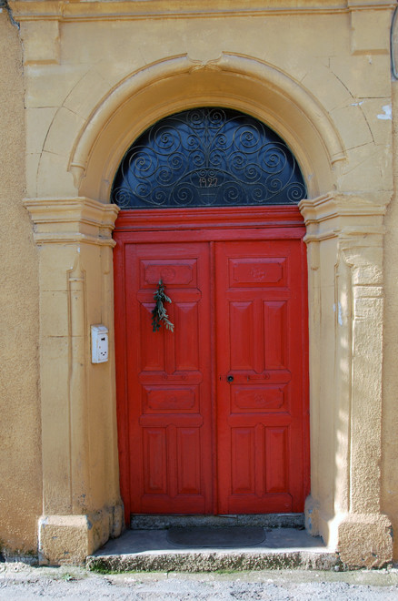 Arched, sandstone doorway with scrolled ironwork dated 1927, Peristerona 