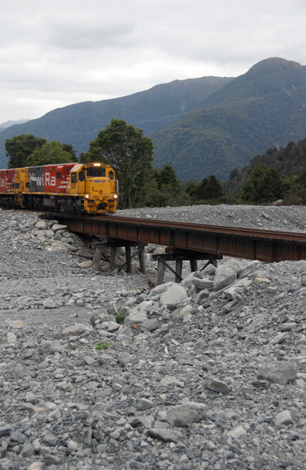 The double-engined Kiwi Rail diesel train pulling up the Otira Valley at the desert-like Kelly's Creek