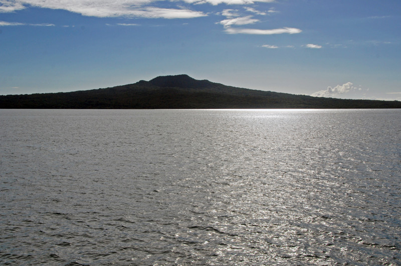 The distinctive shield cone-shaped silhouette of volcanic Rangitoto Island rising to 850 ft. The island was formed only 550-600 years ago.