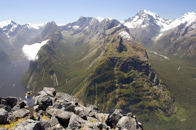 Prof Kurt Cuffey Of UC of Berkeley overlooking the glacier-carved Bowen River drainage (middle), Mount Tutoko (far right) and Milford Sound (left) in Fiordland National Park of New Zealand. (Photo by 