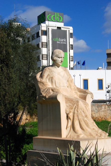 Marble sculpture of seated woman in the grounds of Agios Spyridon Church, Nicosia (with CDB Bnk in background), 2011.