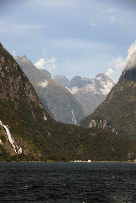 The staggering view back to the boat terminus at Milford Sound and the peaks of the Darran Mountains with their immensely steep slopes carved out of hard Plutonic rocks. Bowen Falls to the left.