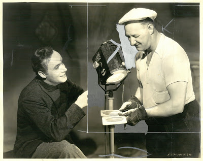 Ping" Bodie (dx) discute dell'illuminazione cinematografica con Charles Boyer sul set di "The Garden of Allah"