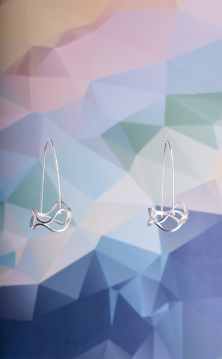 Filigrane Silberohrringe vor geometrischem Farbverlauf – Produktfoto für Kreaia Schmuck und Design