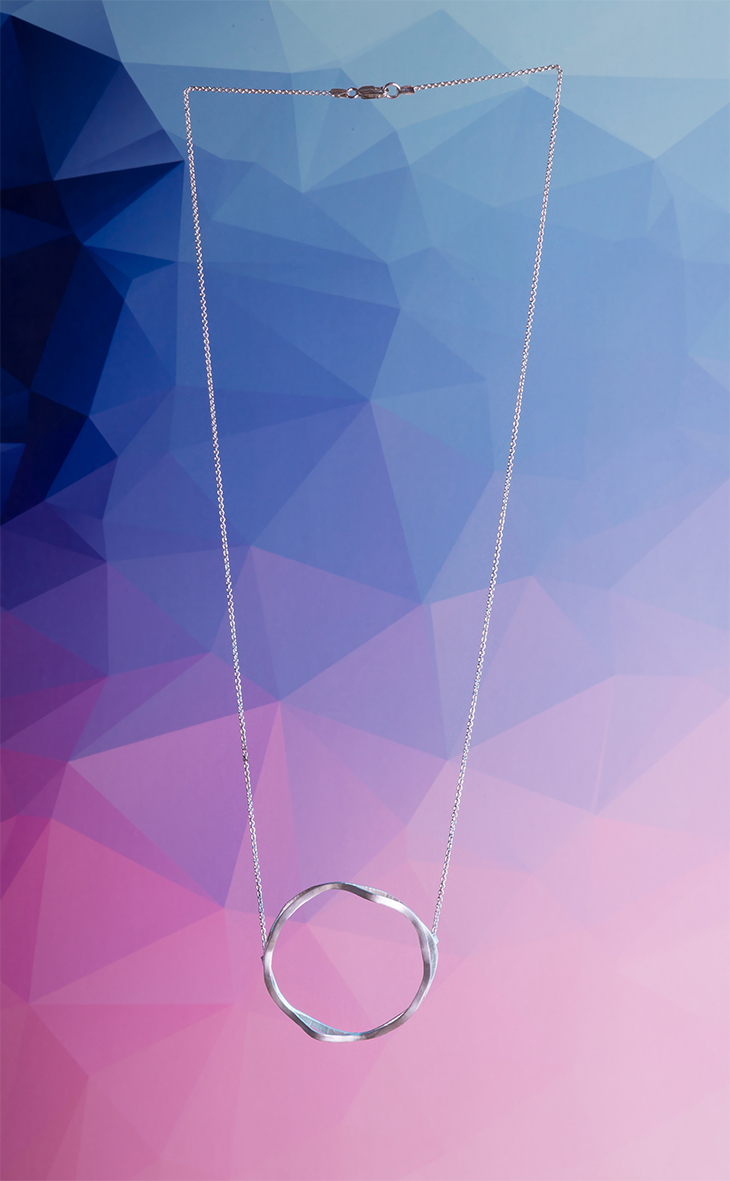 Feine Silberkette mit rundem Anhänger vor blau-rosa Verlaufshintergrund – Produktfoto für Kreaia Schmuck und Design