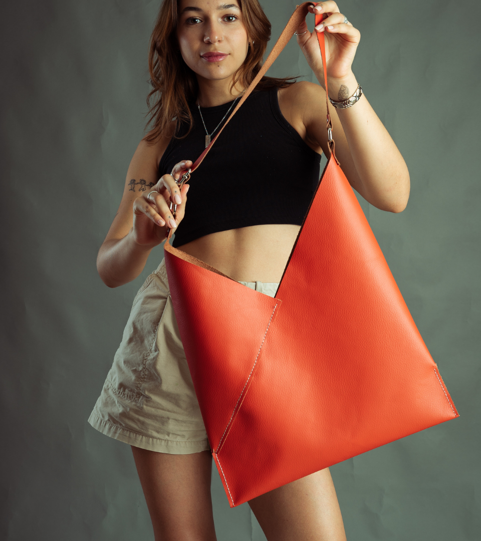 bolso de la colección dopamine  tipo tote con forma triangular de color naranja costurada a maquina, cierra con imán. Hecho en México por Condessa Leather.  