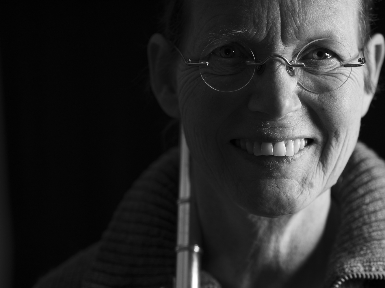Porträt der Musikerin Anne Wiemann. Sie hat ihre Querflöte auf die Schulter gelegt und sieht neugierig ins Bild. Die linke Hälfte vom Gesicht ist im Schatten.