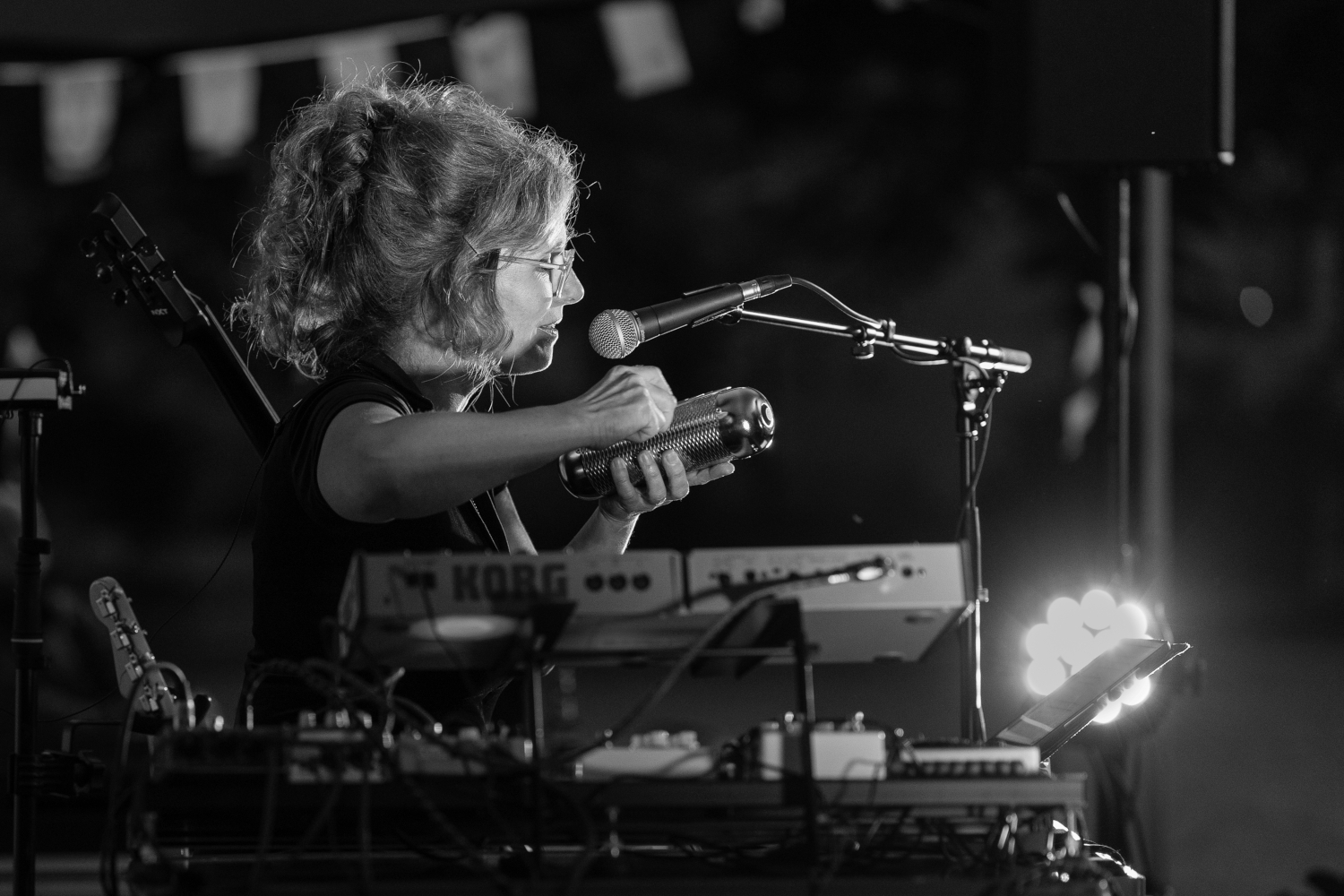 Portrait der Singer Songwriterin und Mulitinistrumentalistin Stefanie Fischer. Schwarzweißfoto, Nahaufnahme im Seitenprofil. Eine Frau mit lockigen hochgesteckten Haaren sitzt hinter mehrern Keyboards und Loopgeräten. Sie singt und spielt gleichzeitig.