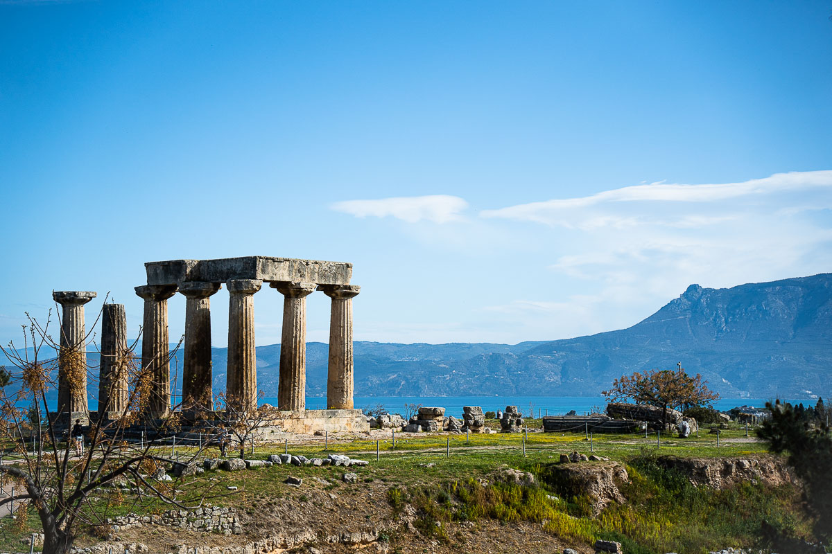 Der antike Apollon-Tempel in der Stadt Korinth und das Meer im Hintergrund.