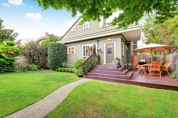 The right deck design can transform a small outdoor space. Wide cascading stairs drop down to an elevated corner patio that provides the perfect amount of room for grilling and dining. 