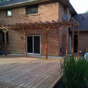 Add character to an expansive platform deck with a sun-shading pergola. Drape the structure in vines to shield the sliding glass doors and brick exterior from the weather.