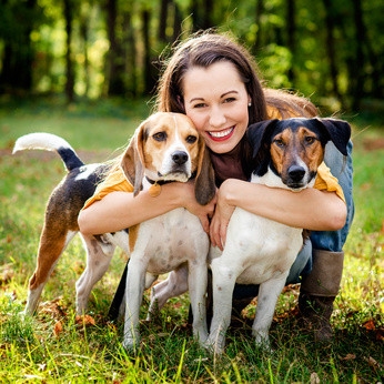 junge Frau umarmt zwei Hunden