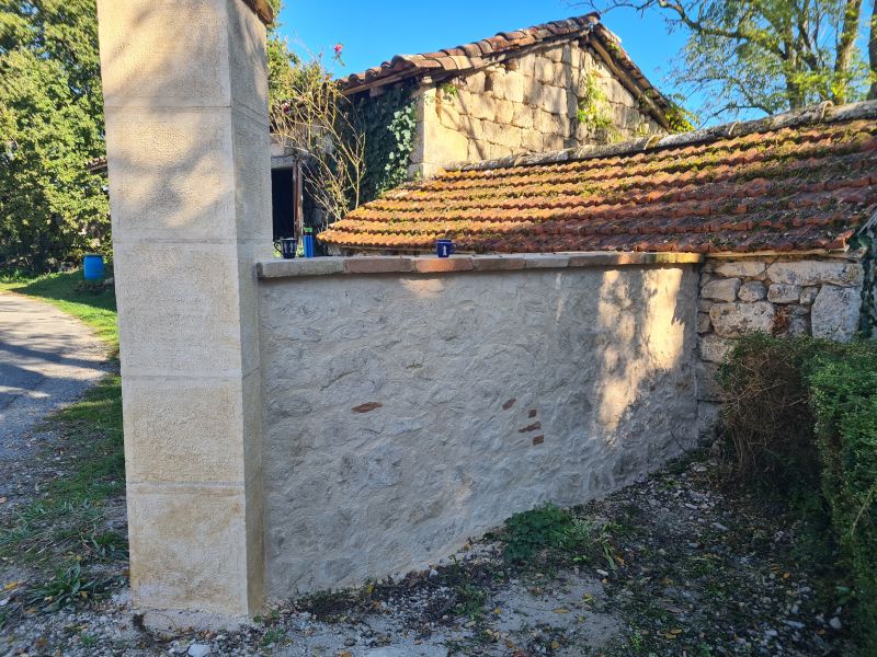 Habillage enduit fausses pierres sur un muret et un poteau d'angle en parpaing