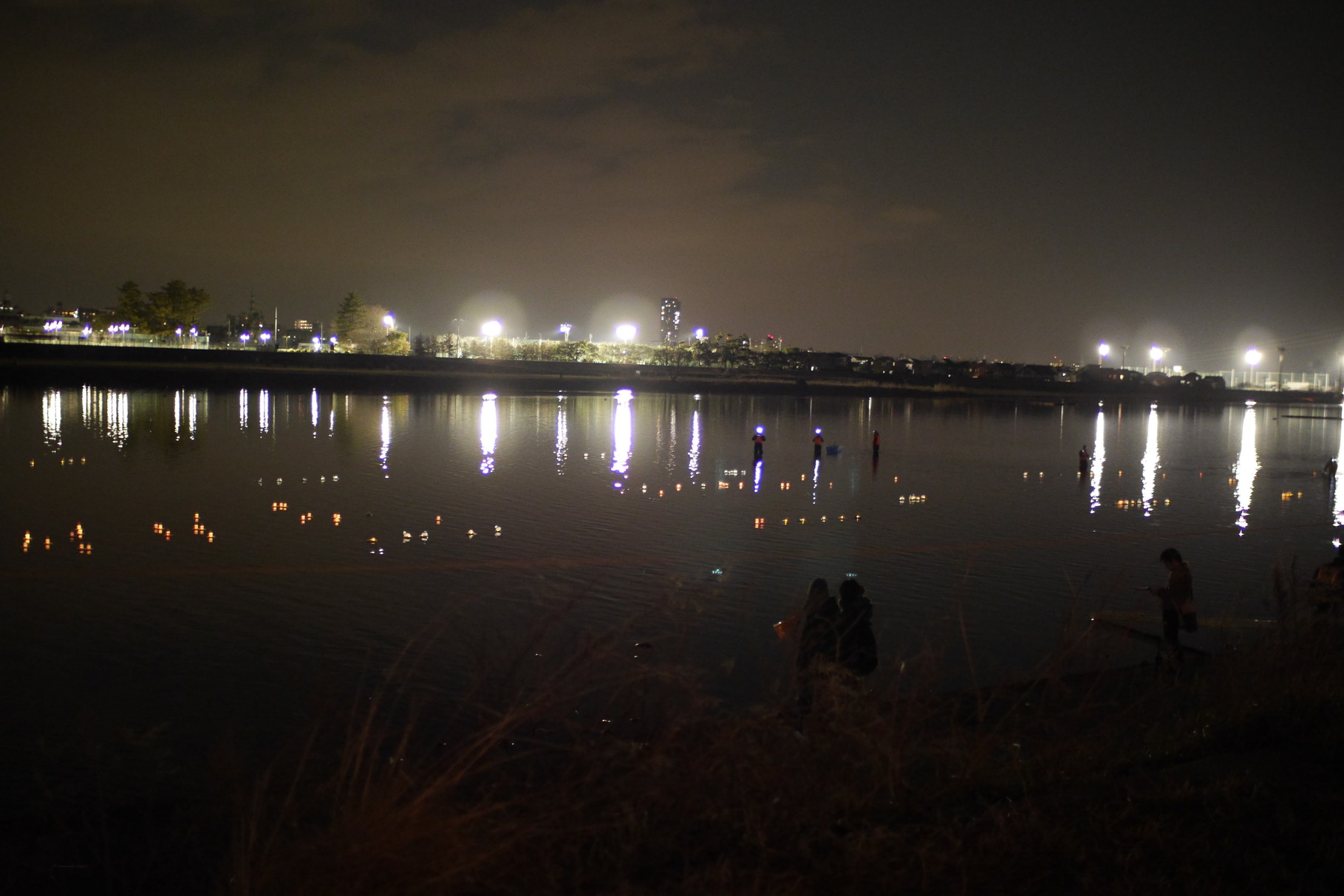 向こう岸は調布市。まぶしい。対岸からの強い調光を受けて、多摩川に漂う灯ろうがよく見えます。