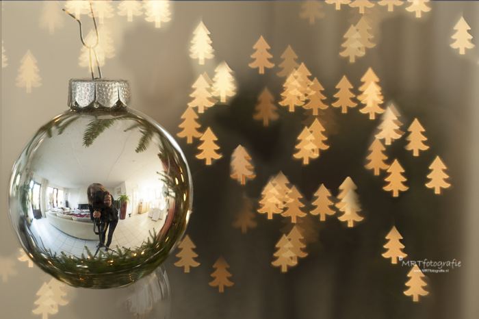 Detail opname van een kerstbal in de boom met  reflectie van mijn persoontje plus een Bokeh figuurtje 