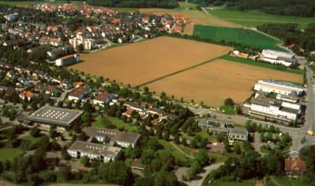 Im Vordergrund ist das Schulhaus und links daneben die Sporthalle.