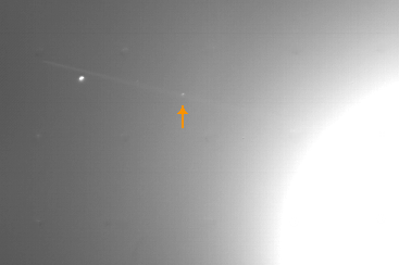 Entdeckungsbild von Adrastea (Pfeil), aufgenommen Voyager 2 am 8. Juli 1979, 23 Stunden vor der größten Annäherung zu Jupiter (heller Schein rechts im Bild).