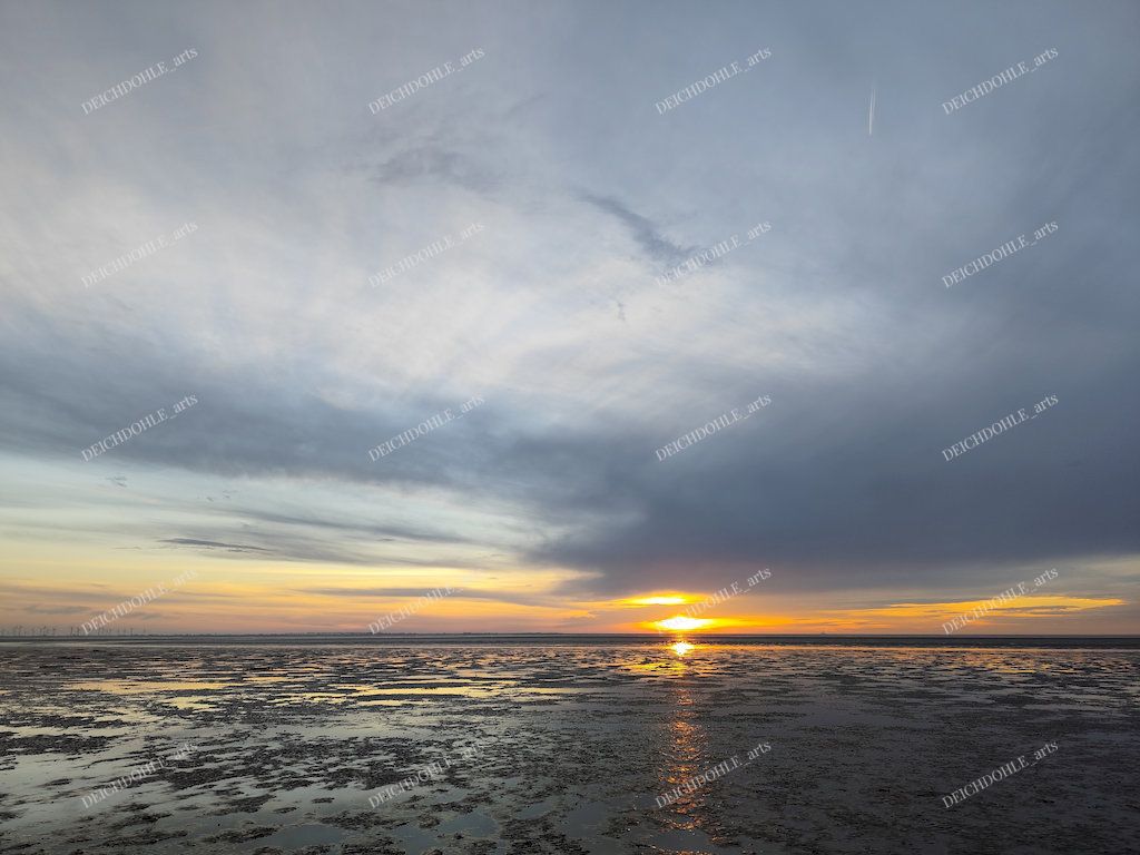Einmaliger Sonnenuntergang zwischen Wolken und Wasseroberfläche an der Nordsee