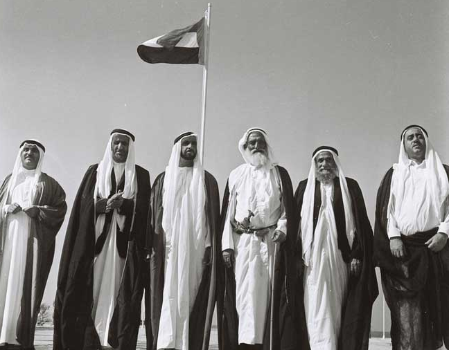 2 DECEMBRE 1971. SOUS LE DRAPEAU DE LA FEDERATION. A g. L'EMIR KHALID BIN MUHAMMAD AL QASIMI. L'EMIRAT DE RAS AL KHAIMAH REJOINDRA LA FEDERATION EN FEVRIER 1972