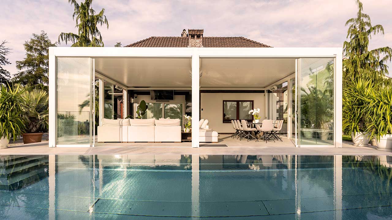 Moderne Lamellendach Pergola am Pool mit schöner Couch und großzügigem Essbereich