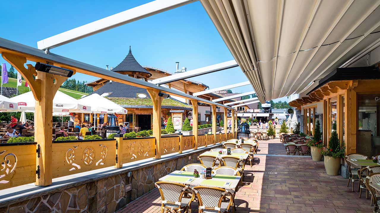 Wandmontierte Pergola mit Faltdach. Flexible Gastronomieüberdachung für die Terrasse.
