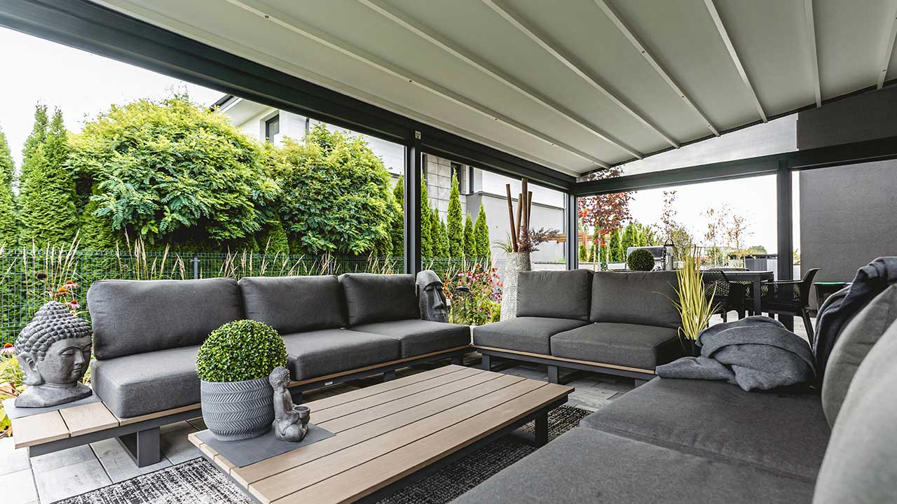 Moderne wandmontierte Pergola im schönen Garten. Terrasse mit Fliesen in Steinoptik.