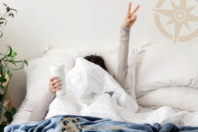 Frau ist im Bett und begrüßt den Tag, hat jedoch noch einen Teebecher in der Hand. Man sollte sich nur auf eine Sache achtsam konzentrieren.