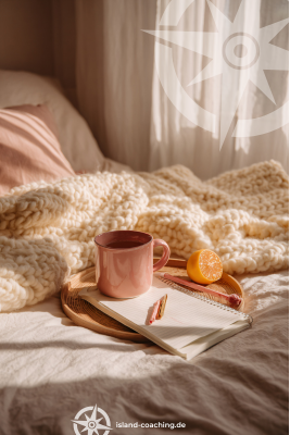 Eine Kuscheldecke liegt auf einem Bett, eine Teetasse steht davor. Selfcare ist kein Luxus, sondern Basis für Stabilität.